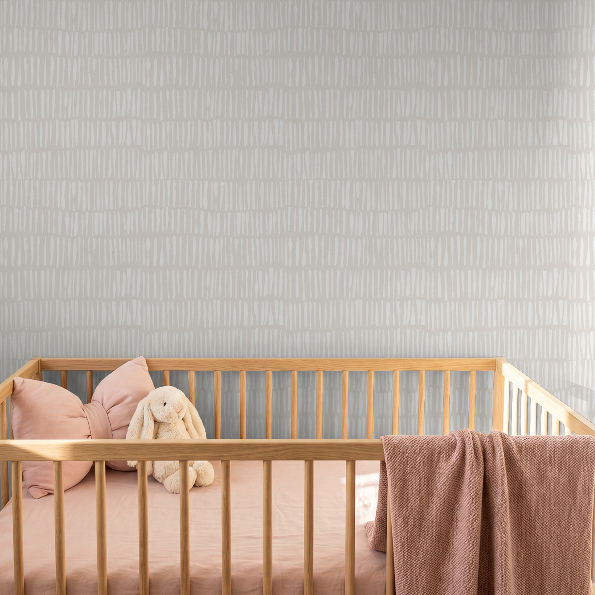Nimbus Veil Greige wallpaper with linear pattern in a nursery with wooden crib.