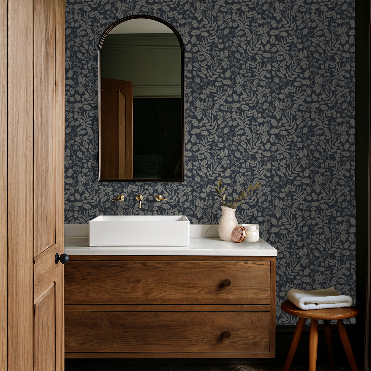 Traditional navy wallpaper with oak leaves and acorns above a warm wood bathroom vanity.