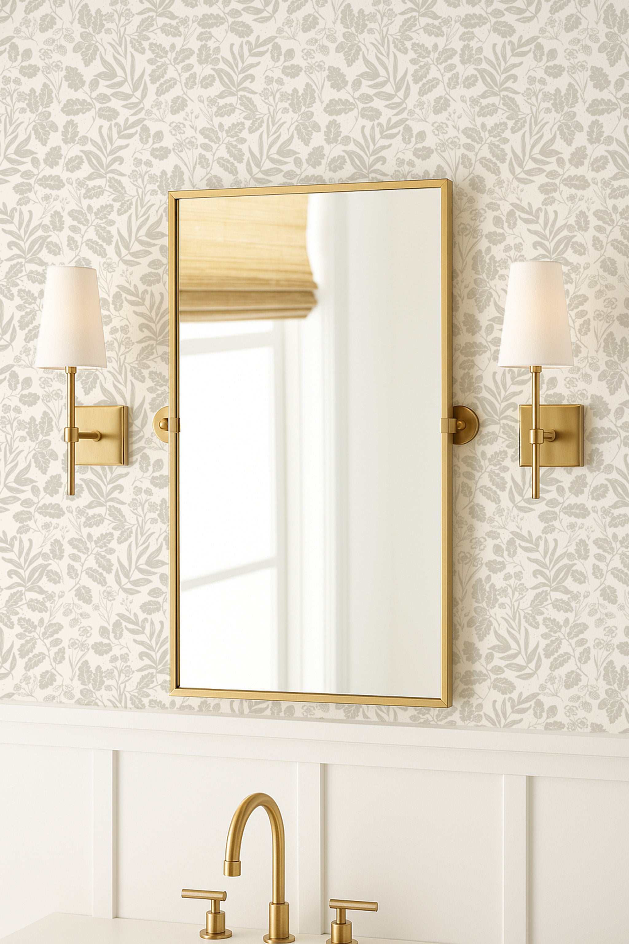 Gold-framed mirror on a wall with decorative neutral tone wallpaper and lighting sconces.