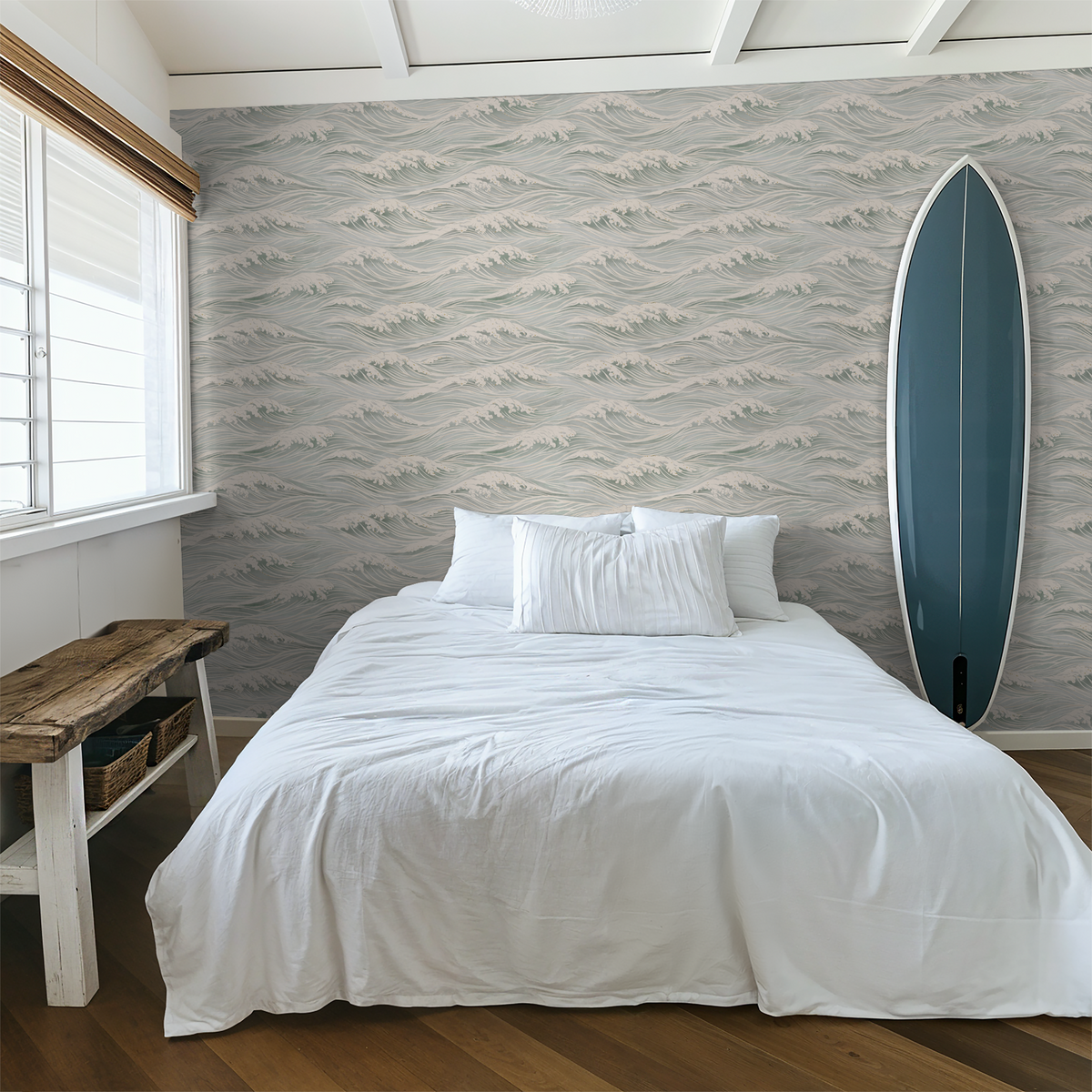 Ocean wave wallpaper in soft blue and ivory behind a white bed with blue surfboard coastal decor.