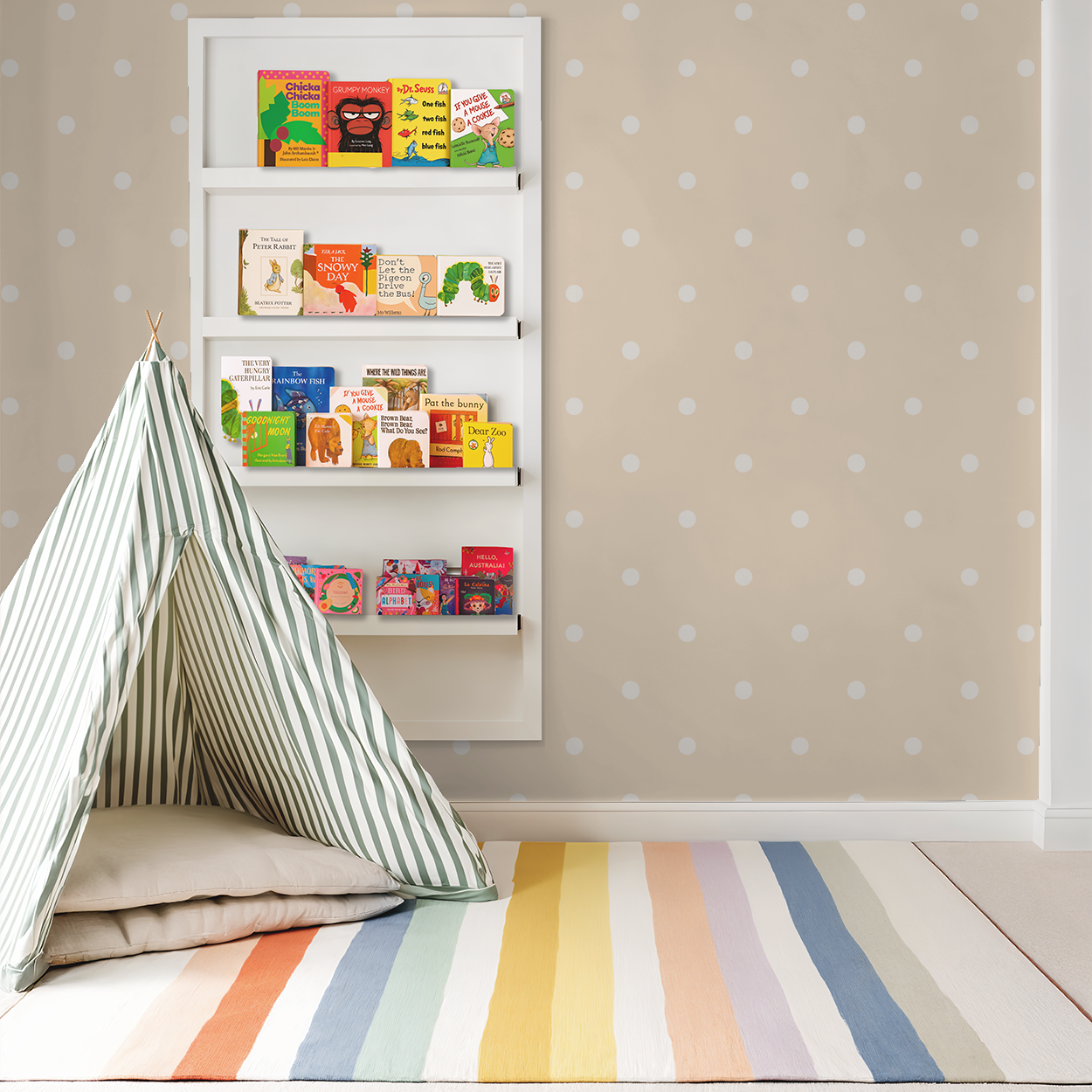 Peach polka dot wallpaper in a playful nursery with a striped tent and colorful books.