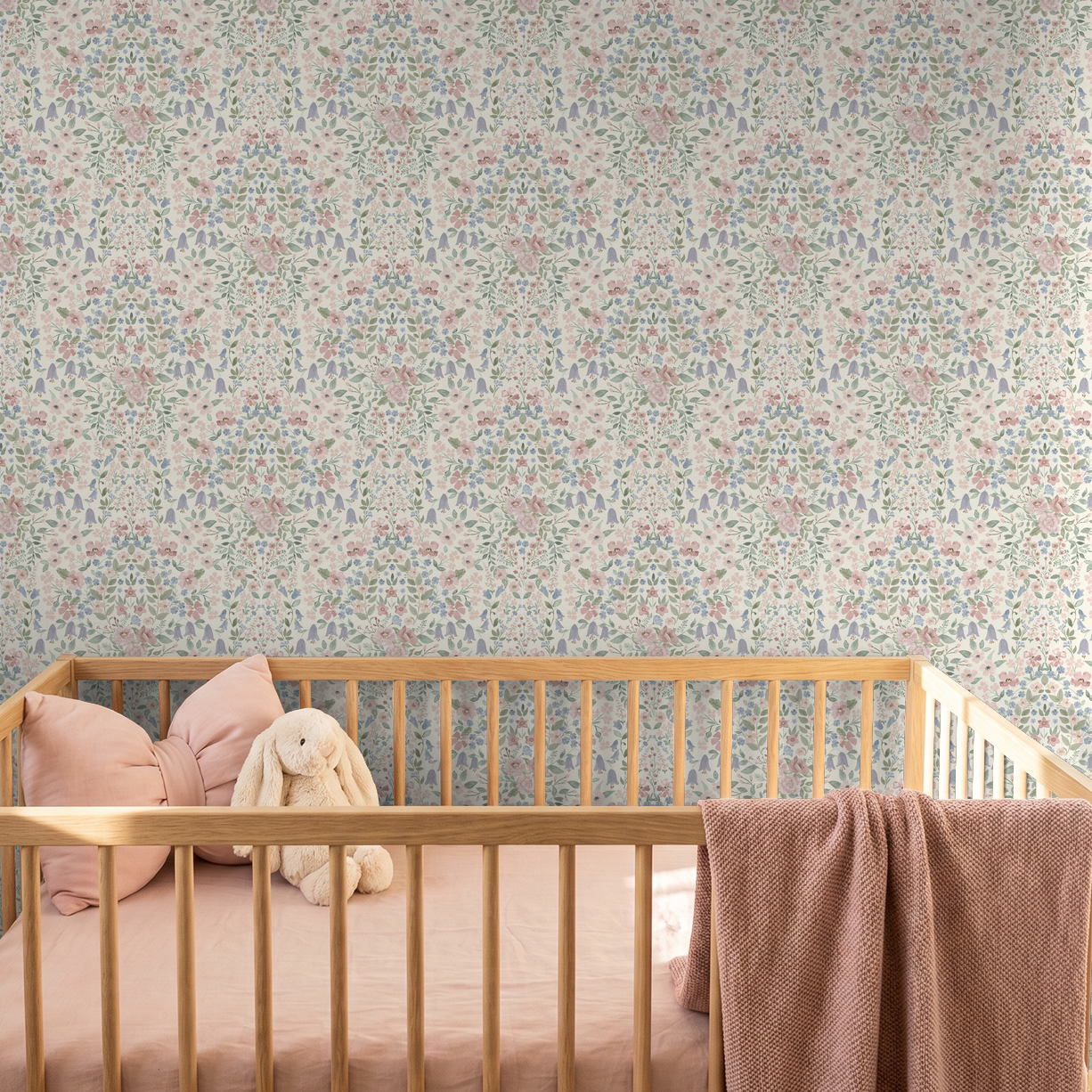 Soft pink floral damask wallpaper in a romantic nursery with natural wood crib and blush bedding.
