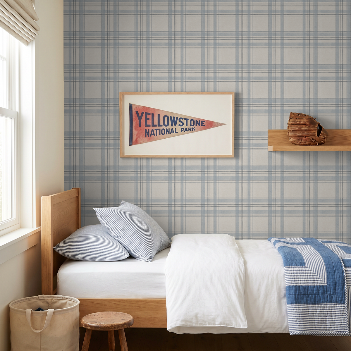 The Blues Plaid wallpaper behind a wooden bed with blue quilt and vintage Yellowstone National Park artwork.