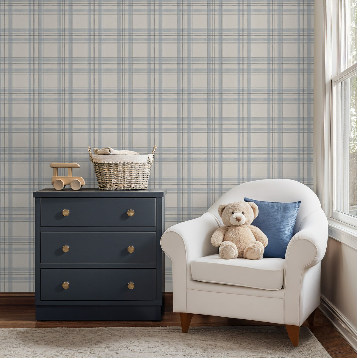 The Blues Plaid wallpaper in a nursery with a navy dresser, white upholstered chair and soft blue checks.
